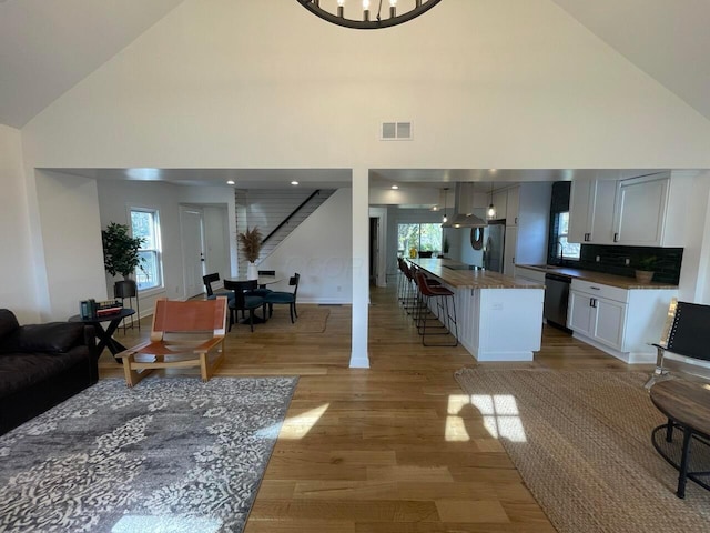 living room with light hardwood / wood-style floors and high vaulted ceiling