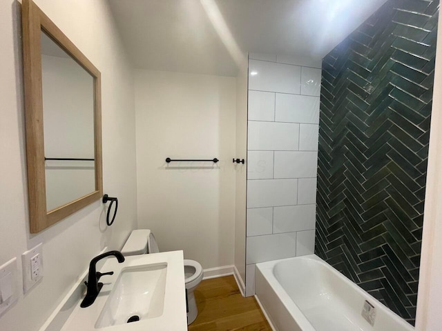 full bathroom with wood-type flooring, tiled shower / bath combo, toilet, and sink