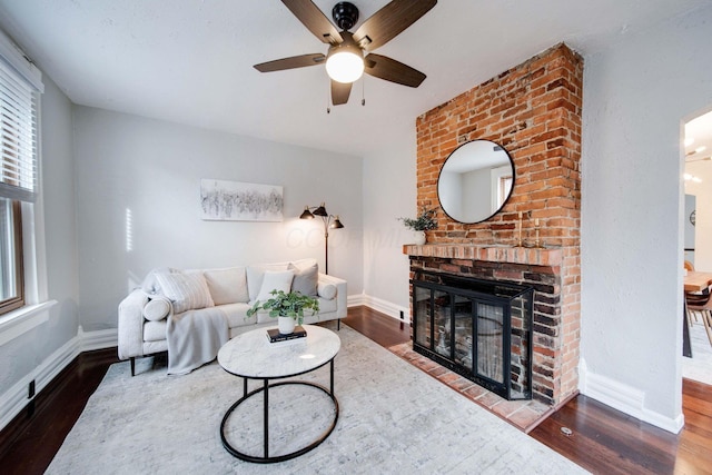 living room with ceiling fan, wood-type flooring, and a brick fireplace