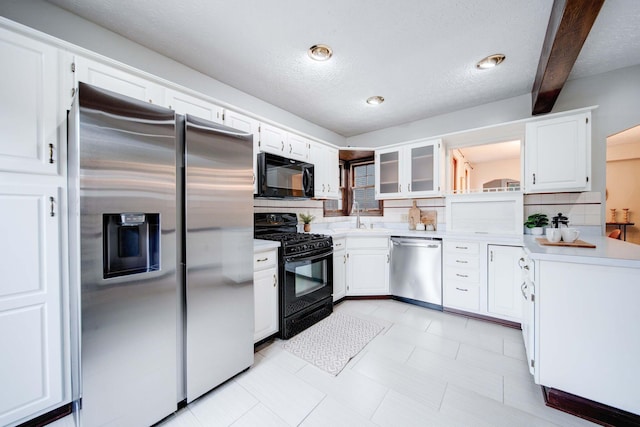 kitchen with tasteful backsplash, sink, black appliances, beam ceiling, and white cabinetry