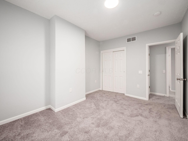 unfurnished bedroom with light carpet and a closet