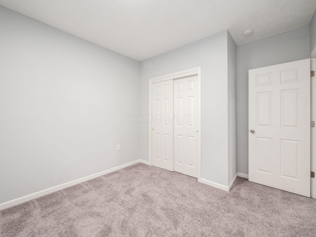 unfurnished bedroom with light colored carpet and a closet