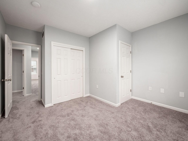 unfurnished bedroom with light colored carpet and a closet