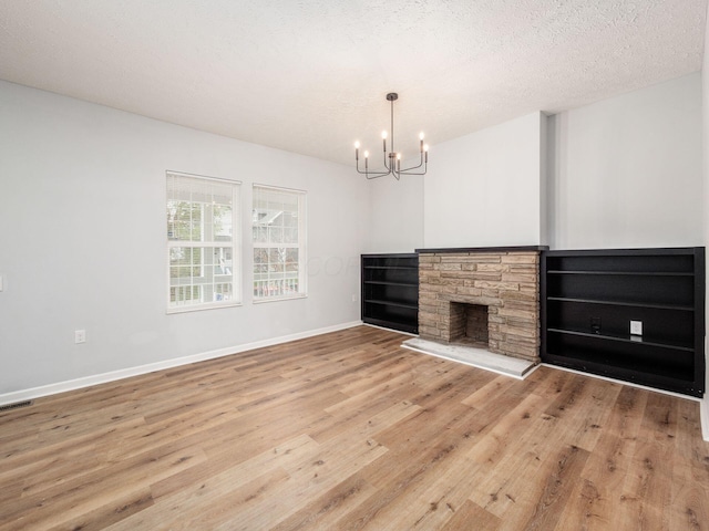 unfurnished living room with a chandelier, hardwood / wood-style floors, a textured ceiling, and a fireplace