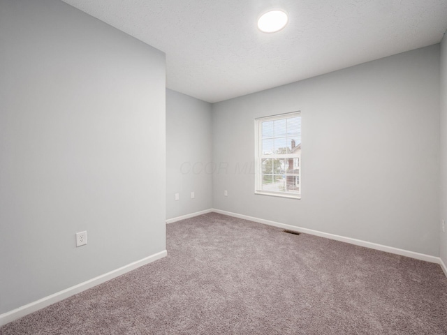 carpeted empty room featuring a textured ceiling