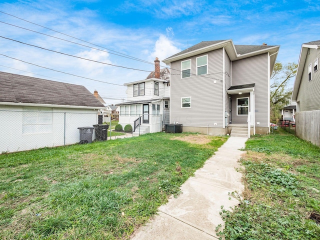 rear view of house featuring a yard and central AC unit