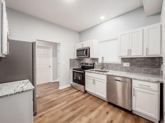 kitchen featuring light stone countertops, stainless steel appliances, white cabinetry, and light hardwood / wood-style floors