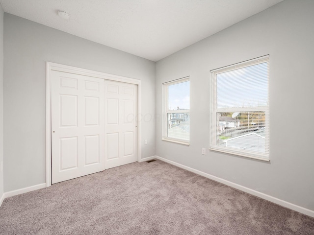 unfurnished bedroom featuring light colored carpet and a closet