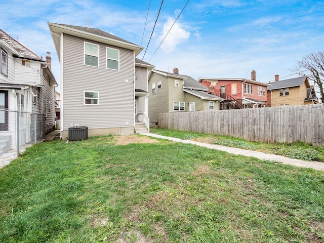 back of property featuring a lawn and central air condition unit