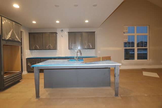 kitchen with decorative backsplash, dark brown cabinetry, a center island with sink, and lofted ceiling