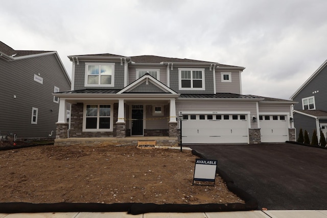 craftsman-style home with a standing seam roof, a porch, stone siding, aphalt driveway, and metal roof