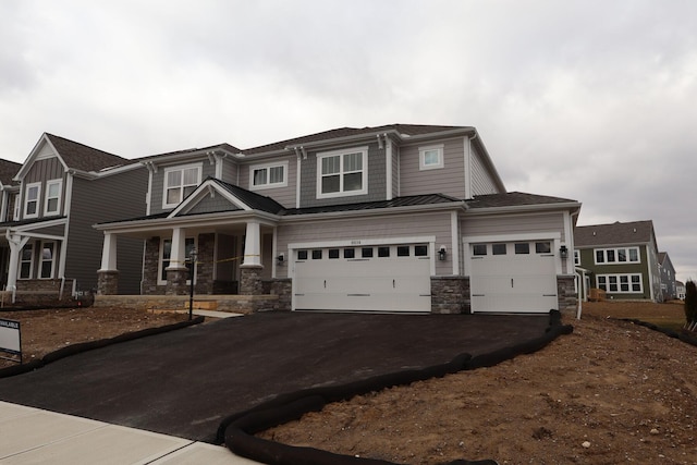 view of front of property with an attached garage, a porch, metal roof, driveway, and a standing seam roof