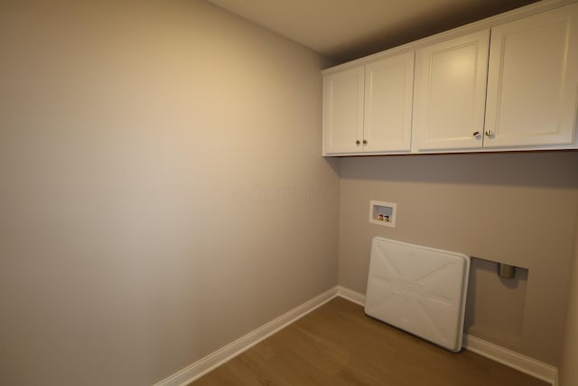 laundry room with cabinet space, wood finished floors, baseboards, and washer hookup