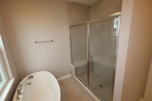 bathroom featuring tile patterned floors, baseboards, a freestanding bath, and a stall shower