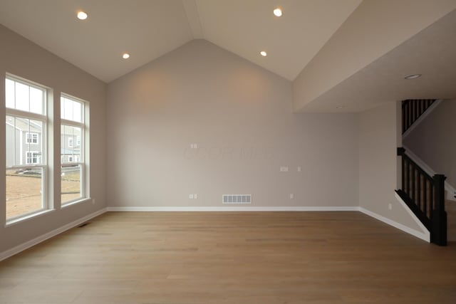 unfurnished room with light wood-type flooring, visible vents, baseboards, stairs, and vaulted ceiling