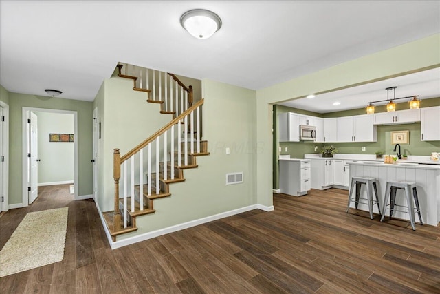 kitchen featuring white cabinets, hanging light fixtures, dark wood-type flooring, and a breakfast bar area