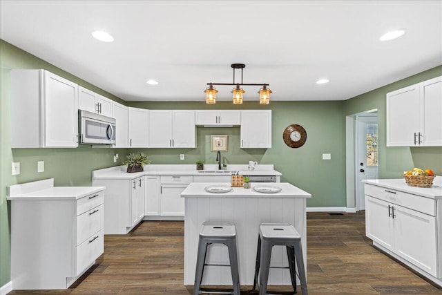 kitchen with white cabinets, dark hardwood / wood-style flooring, a kitchen island, and sink