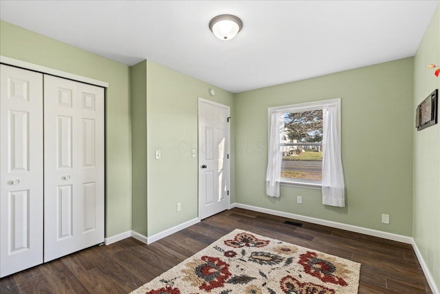 unfurnished bedroom with dark wood-type flooring and a closet