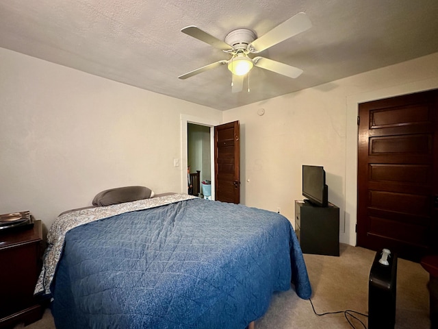 carpeted bedroom with ceiling fan and a textured ceiling