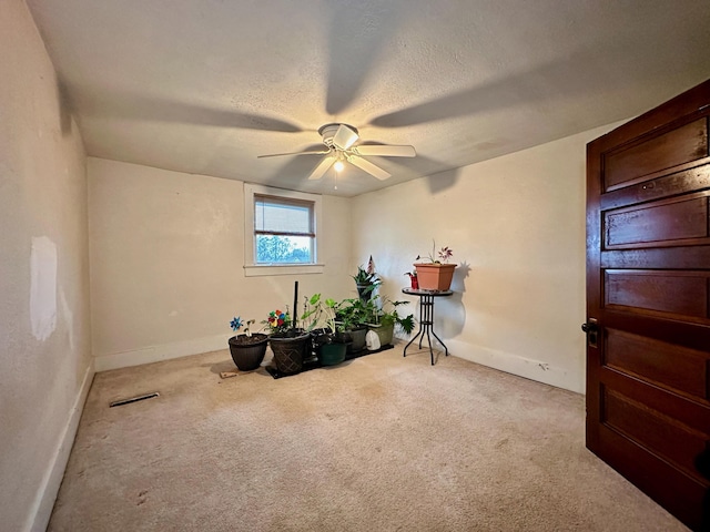 misc room featuring light carpet, ceiling fan, and a textured ceiling