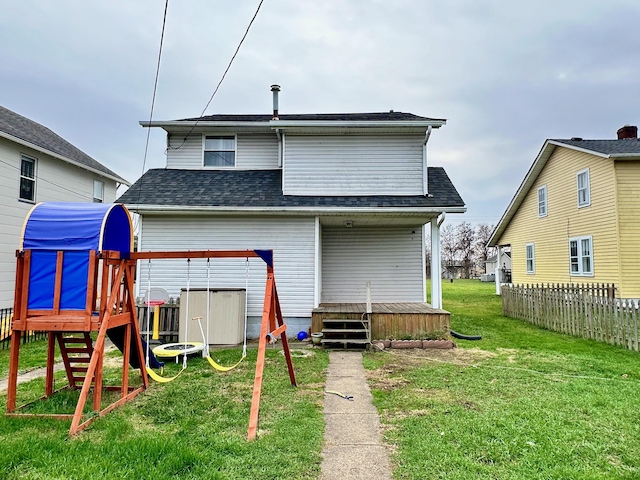 back of house featuring a playground and a yard