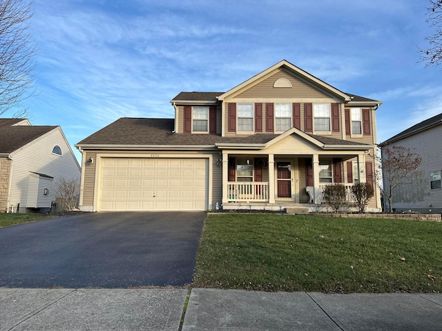 view of front of property featuring covered porch, a garage, and a front lawn