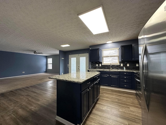 kitchen featuring decorative backsplash, appliances with stainless steel finishes, a textured ceiling, ceiling fan, and a kitchen island