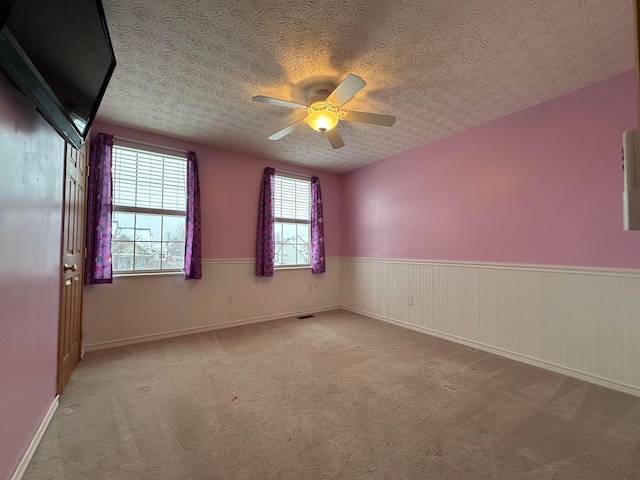 spare room with ceiling fan, light carpet, and a textured ceiling