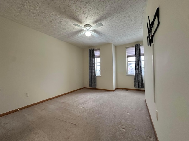 unfurnished room with ceiling fan, light colored carpet, and a textured ceiling