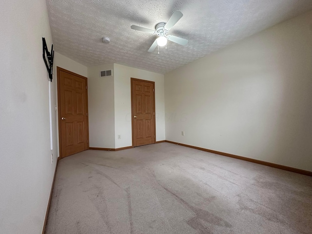 spare room with a textured ceiling, ceiling fan, and light carpet