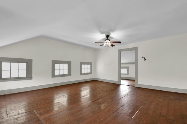 empty room with dark hardwood / wood-style flooring, vaulted ceiling, plenty of natural light, and ceiling fan