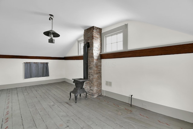 interior space with light hardwood / wood-style floors, lofted ceiling, and a wood stove