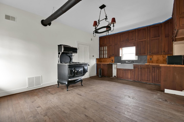 kitchen featuring a wood stove, pendant lighting, wood-type flooring, and extractor fan