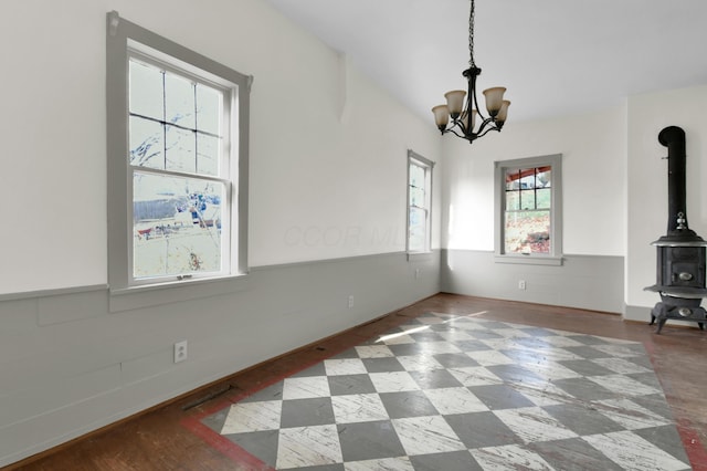 unfurnished dining area with a wood stove, plenty of natural light, and a notable chandelier