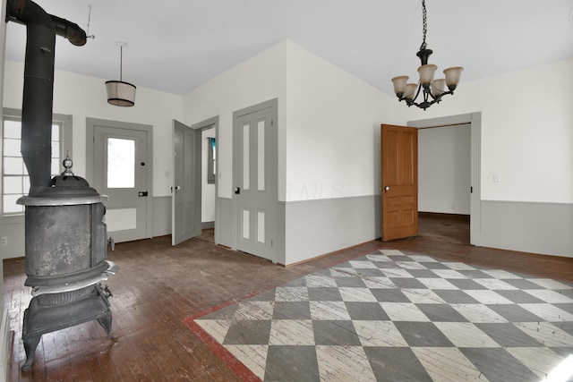 foyer with a wood stove, a chandelier, and hardwood / wood-style flooring