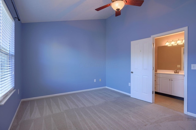 unfurnished bedroom featuring sink, vaulted ceiling, ceiling fan, connected bathroom, and light colored carpet