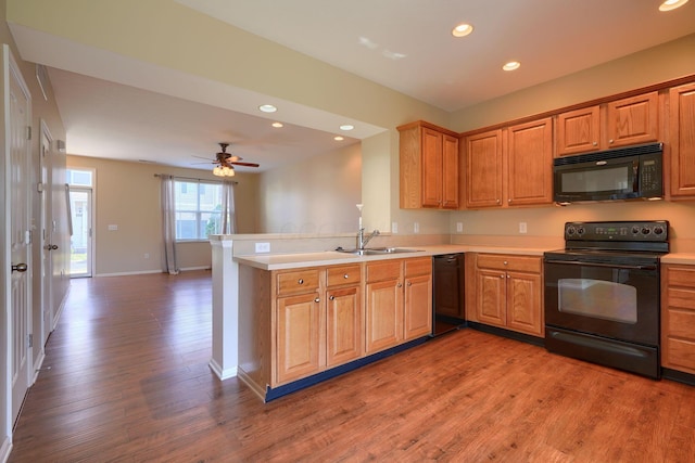 kitchen featuring kitchen peninsula, ceiling fan, sink, black appliances, and hardwood / wood-style floors