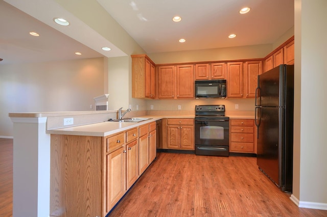 kitchen featuring black appliances, sink, kitchen peninsula, and hardwood / wood-style floors