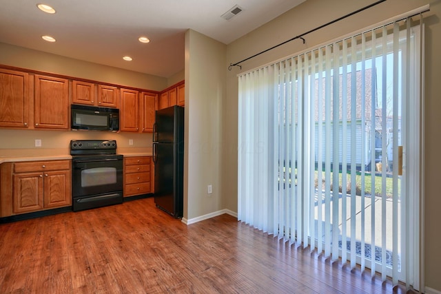 kitchen with hardwood / wood-style flooring, a wealth of natural light, and black appliances