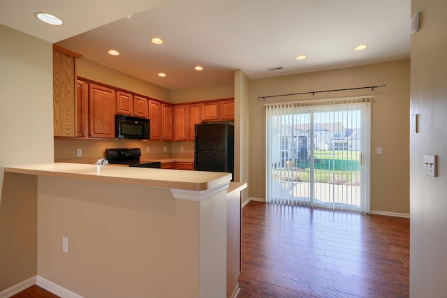 kitchen with black appliances, kitchen peninsula, and hardwood / wood-style floors