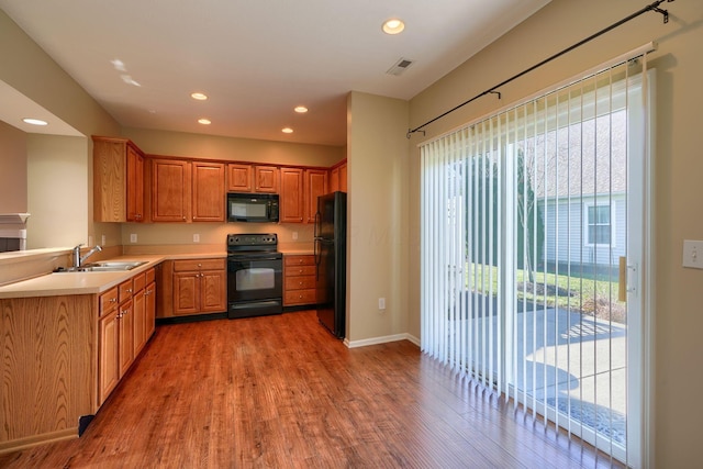 kitchen featuring dark hardwood / wood-style flooring, sink, a healthy amount of sunlight, and black appliances