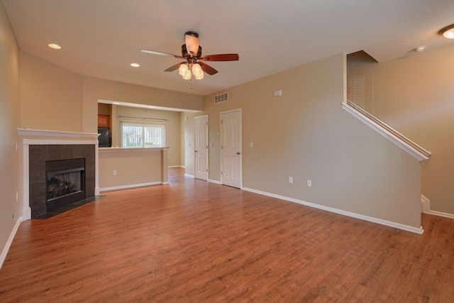 unfurnished living room featuring a tile fireplace, ceiling fan, and hardwood / wood-style flooring