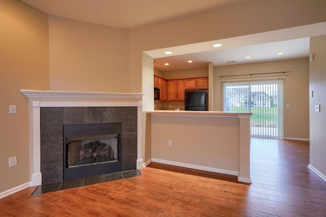 unfurnished living room with hardwood / wood-style flooring and a tiled fireplace