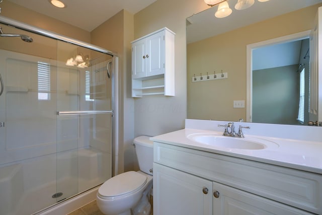 bathroom with a shower with door, vanity, and toilet