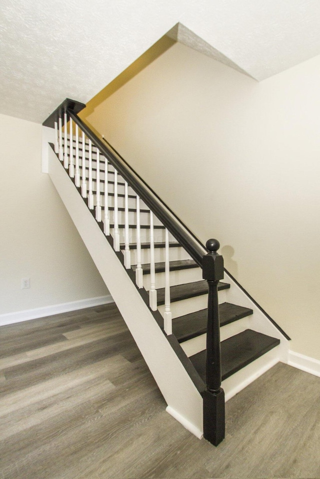 staircase with a textured ceiling and hardwood / wood-style flooring