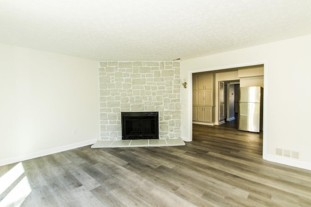 unfurnished living room featuring a fireplace, a textured ceiling, and dark hardwood / wood-style flooring