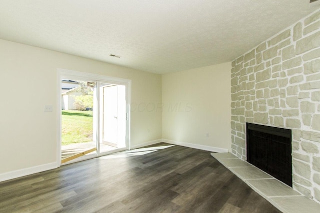 unfurnished living room with hardwood / wood-style flooring, a stone fireplace, and a textured ceiling