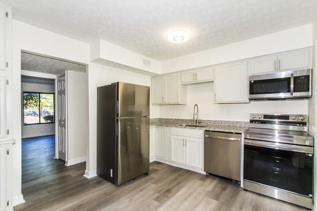 kitchen with hardwood / wood-style flooring, sink, a textured ceiling, and appliances with stainless steel finishes