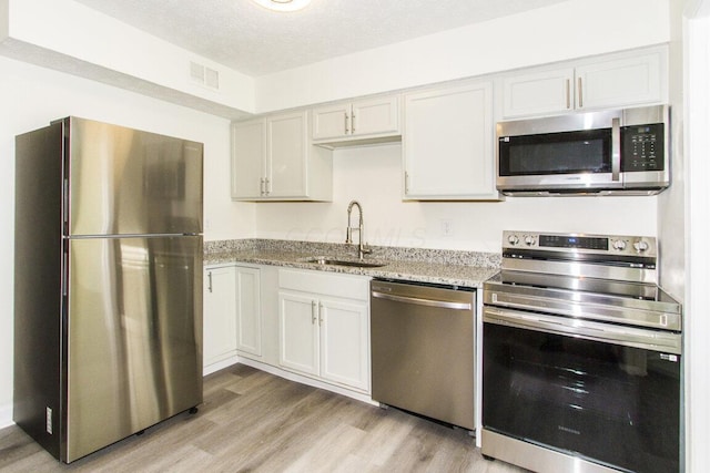 kitchen with white cabinetry, sink, light hardwood / wood-style flooring, a textured ceiling, and appliances with stainless steel finishes