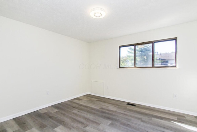 spare room featuring dark hardwood / wood-style floors and a textured ceiling